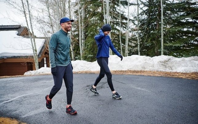 Två personer tränar utomhus i lager på en snöig vår- eller höstdag