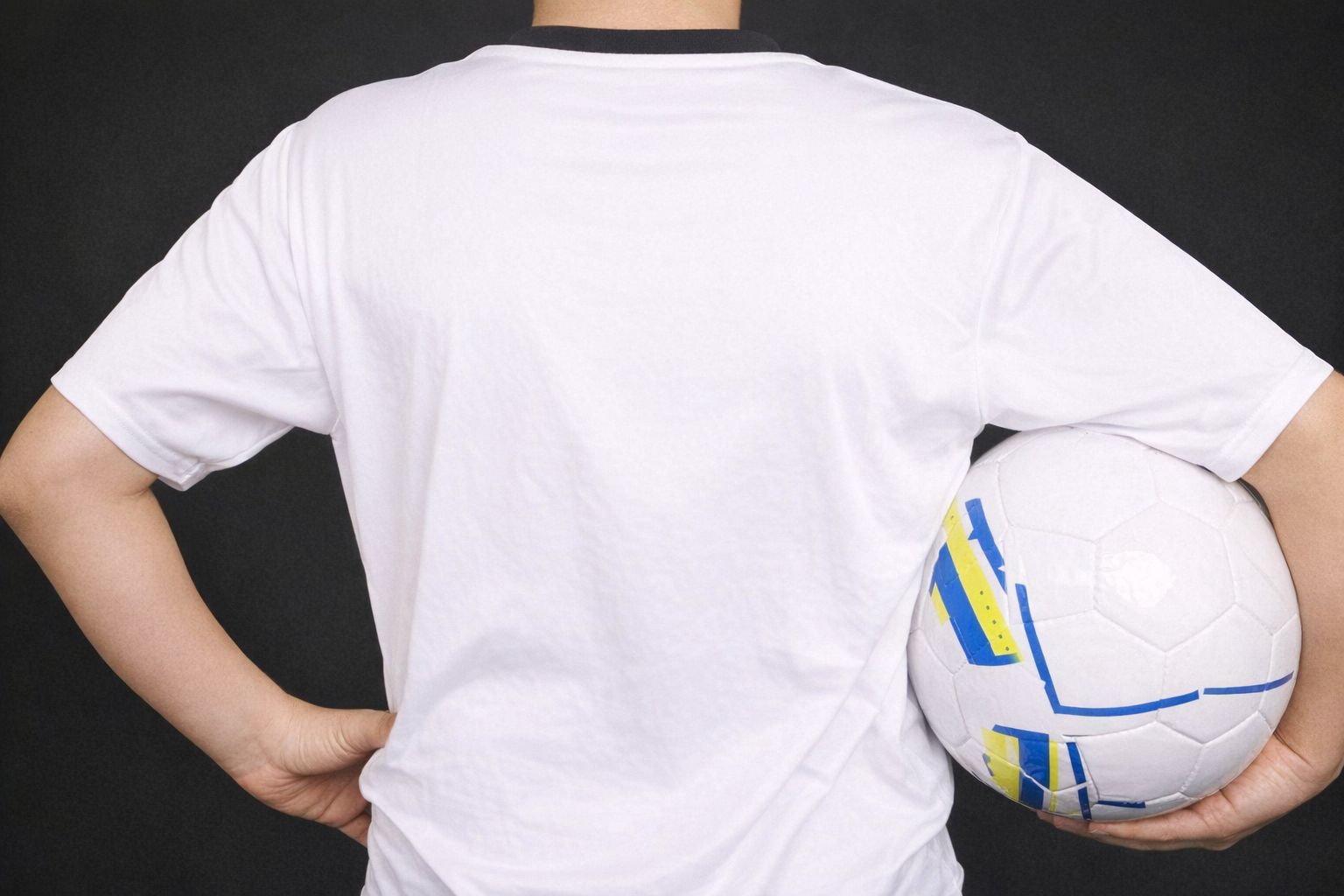 Baksidan av en vit sporttröja utan tryck som hålls av en person med en fotboll.